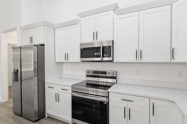 kitchen with light wood finished floors, appliances with stainless steel finishes, and white cabinets