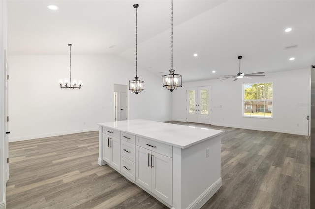 kitchen featuring a center island, white cabinets, ceiling fan with notable chandelier, and light wood-style flooring