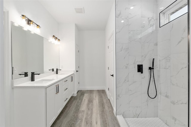 full bath featuring double vanity, a marble finish shower, and a sink