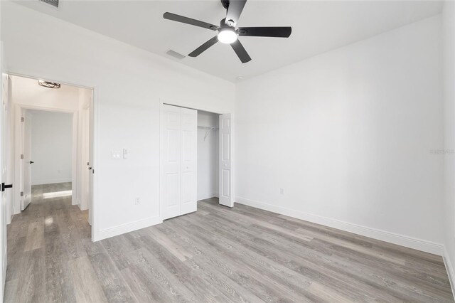 unfurnished bedroom with a closet, baseboards, visible vents, and light wood-type flooring