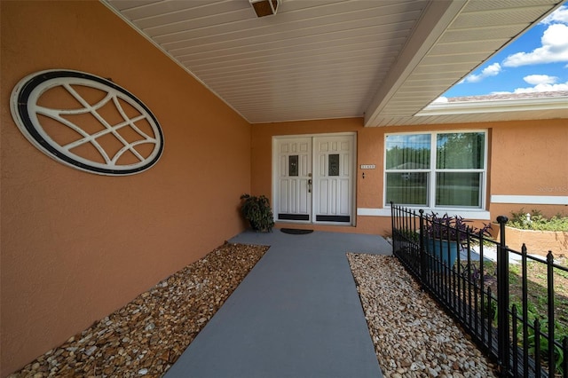 entrance to property with stucco siding and fence