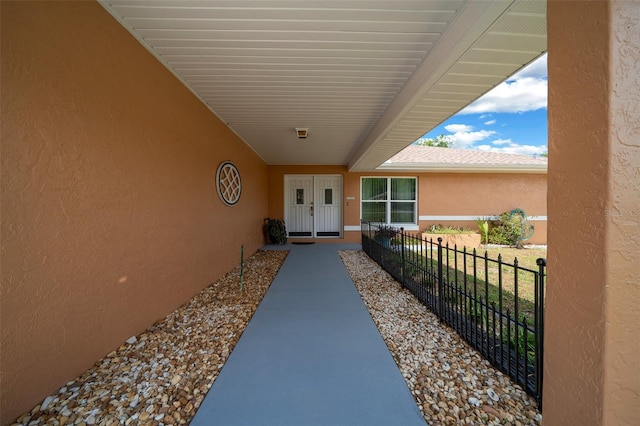 doorway to property with fence and stucco siding