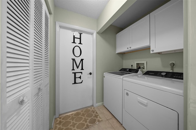 laundry room with a textured ceiling, washing machine and dryer, cabinet space, baseboards, and light tile patterned flooring