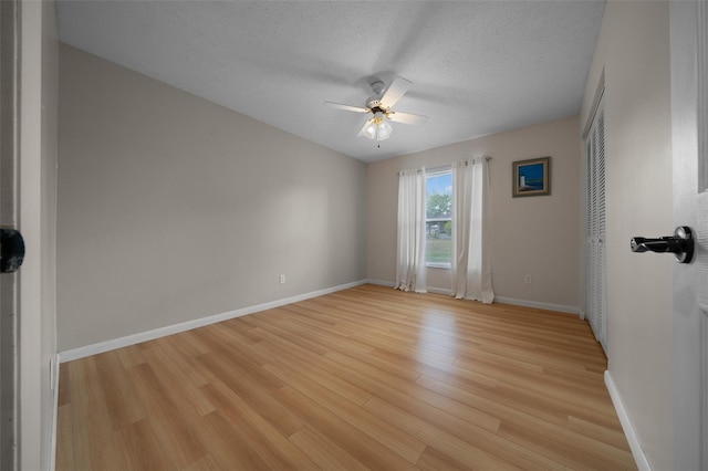 unfurnished room featuring light wood-style floors, baseboards, ceiling fan, and a textured ceiling