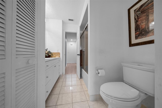 full bathroom featuring tile patterned flooring, toilet, baseboards, bath / shower combo with glass door, and a closet