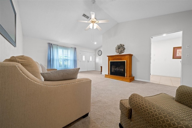 living room featuring light carpet, visible vents, a fireplace with raised hearth, a ceiling fan, and vaulted ceiling