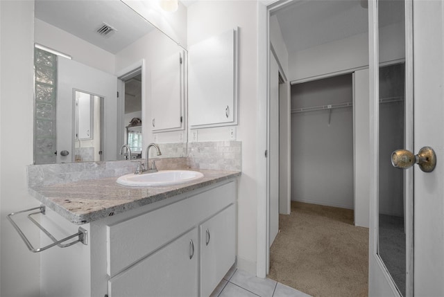 bathroom with tile patterned floors, visible vents, a walk in closet, and vanity