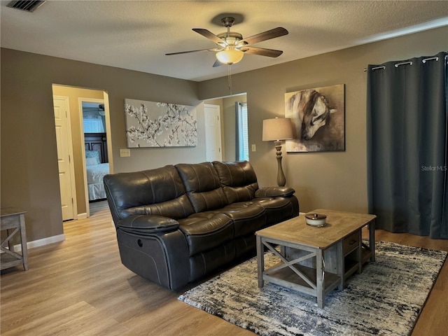 living area with a ceiling fan, a textured ceiling, visible vents, and light wood-style floors