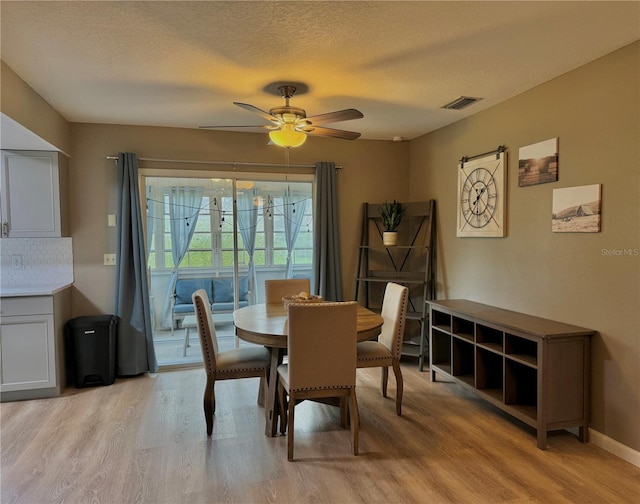 dining space with visible vents, a textured ceiling, light wood finished floors, and ceiling fan