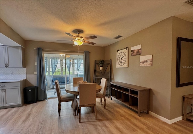 dining room with ceiling fan, light wood finished floors, a textured ceiling, and visible vents