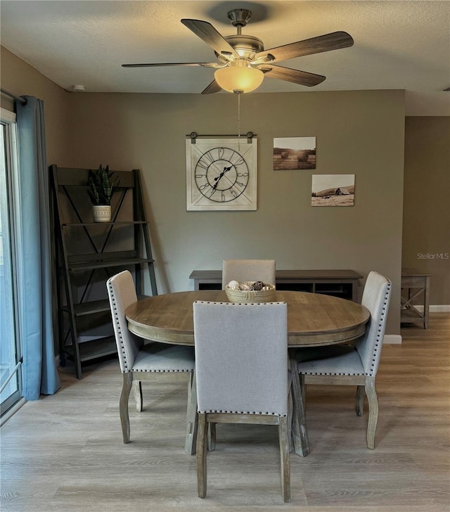 dining area featuring baseboards, a ceiling fan, and light wood-type flooring
