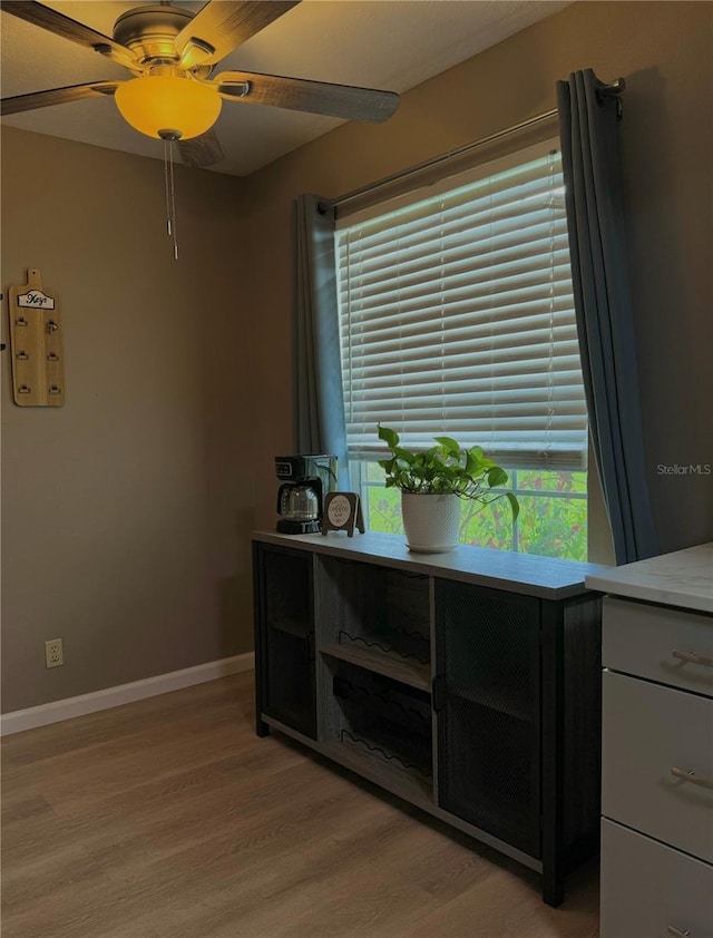 interior space with light wood-style floors, baseboards, and ceiling fan