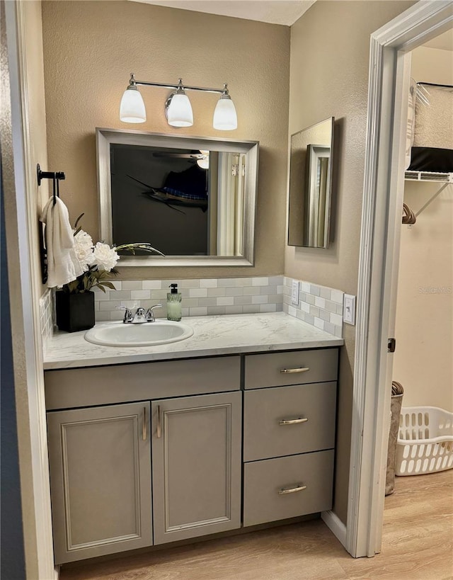 bathroom with vanity, decorative backsplash, and wood finished floors