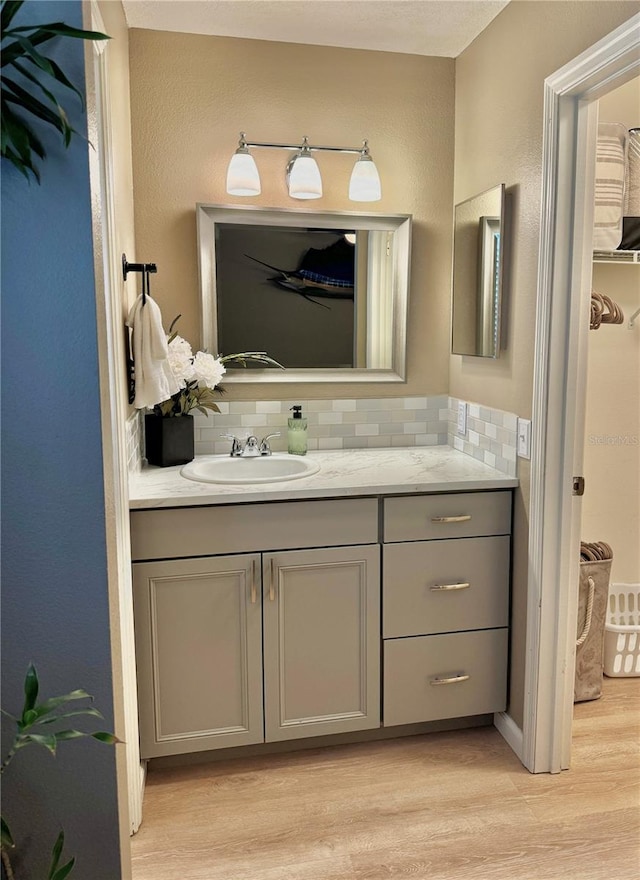 bathroom with decorative backsplash, wood finished floors, and vanity