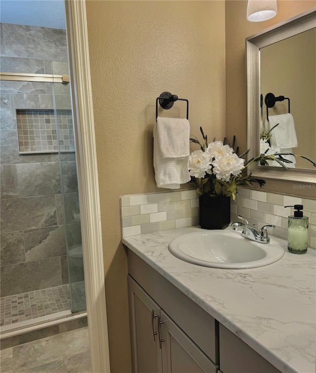 bathroom featuring vanity, decorative backsplash, and a shower stall