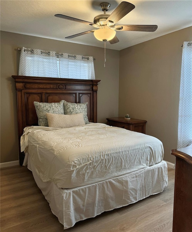 bedroom with light wood-style floors, baseboards, and ceiling fan