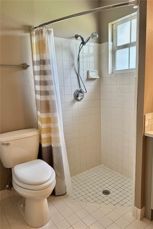 bathroom with tile patterned floors, a textured wall, and a stall shower