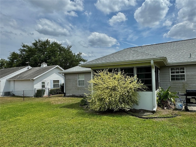 back of property with a lawn, fence, and roof with shingles