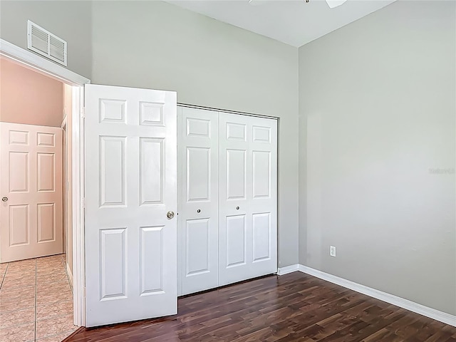 unfurnished bedroom with baseboards, visible vents, dark wood-style floors, and a closet