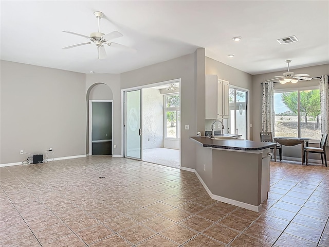 kitchen featuring visible vents, baseboards, ceiling fan, and dark countertops