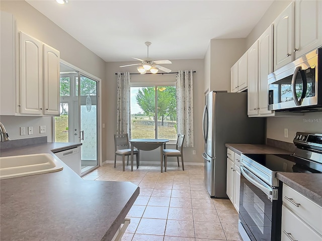 kitchen featuring stainless steel appliances, dark countertops, a wealth of natural light, and a sink