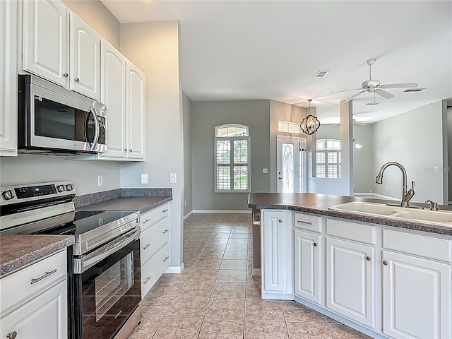 kitchen featuring ceiling fan, dark countertops, appliances with stainless steel finishes, and a sink