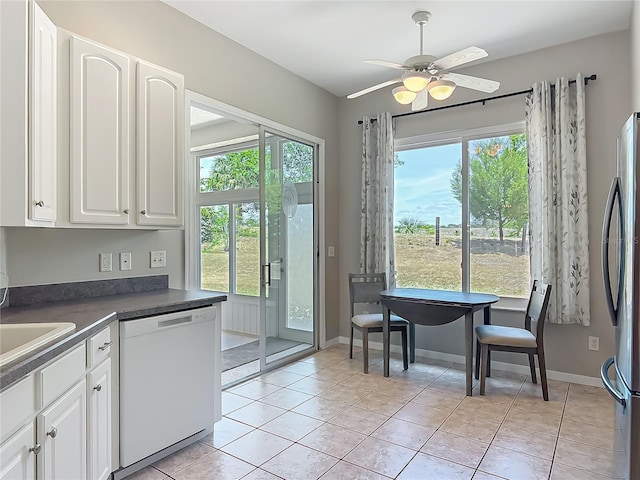 kitchen featuring white dishwasher, dark countertops, white cabinets, and freestanding refrigerator
