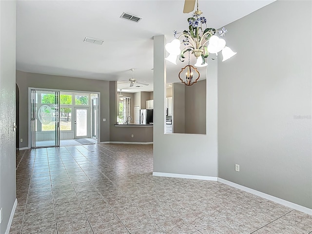 unfurnished room featuring baseboards, visible vents, a sink, and ceiling fan with notable chandelier