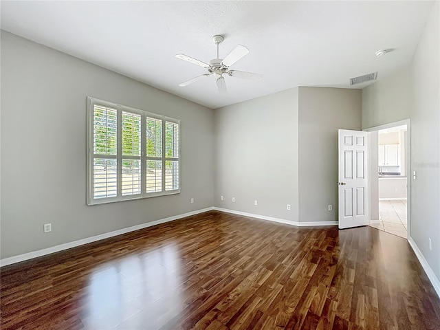 spare room with visible vents, a ceiling fan, baseboards, and wood finished floors