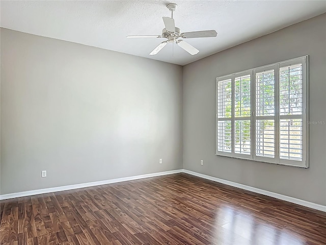 empty room with baseboards, a ceiling fan, dark wood-style floors, and a textured ceiling