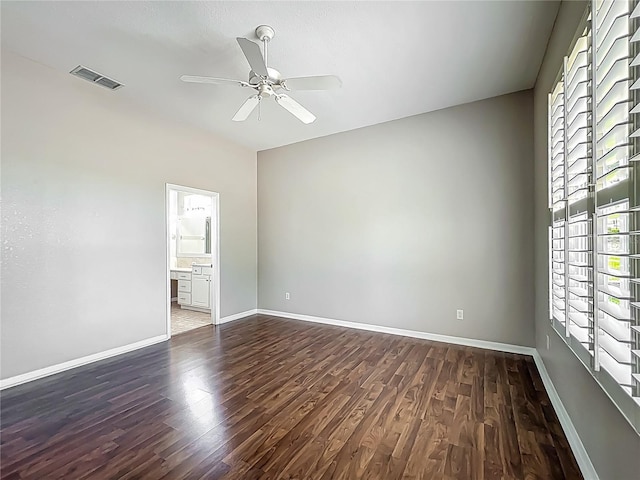 empty room with visible vents, a ceiling fan, dark wood-style flooring, and baseboards