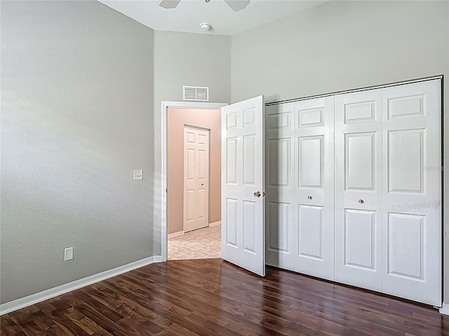 unfurnished bedroom featuring ceiling fan, visible vents, wood finished floors, baseboards, and a closet