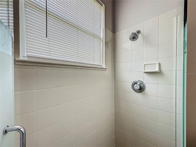 full bathroom featuring a tile shower and a wealth of natural light