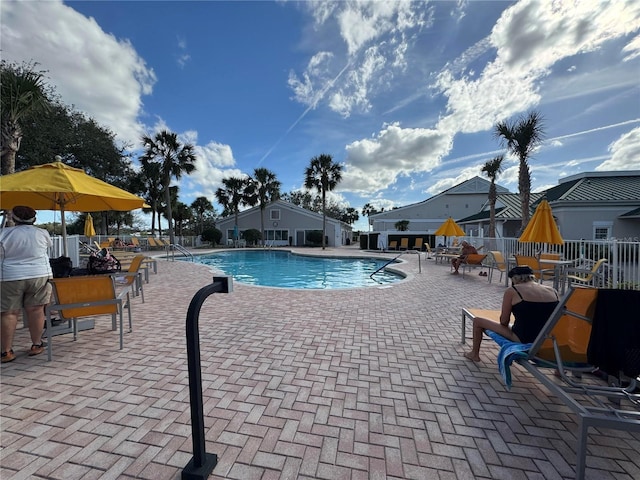 community pool with a patio and fence
