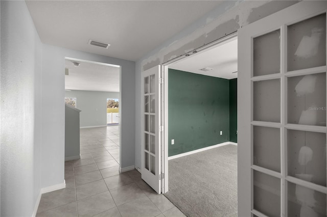 corridor featuring visible vents, baseboards, and tile patterned floors