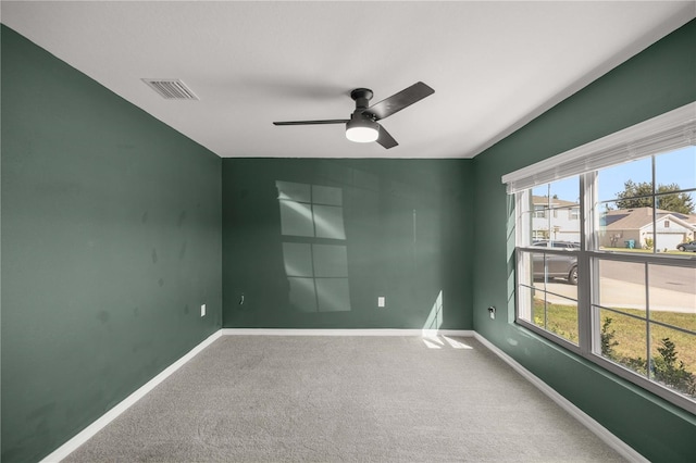 carpeted empty room featuring baseboards, ceiling fan, and visible vents