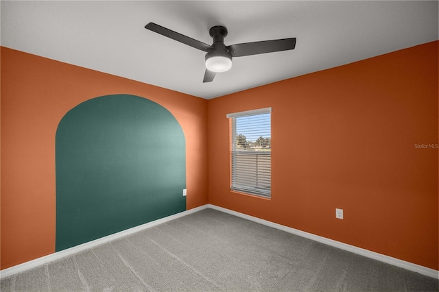 spare room with carpet floors, a ceiling fan, and baseboards