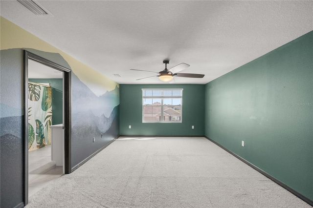 empty room featuring visible vents, a ceiling fan, carpet, and a textured ceiling