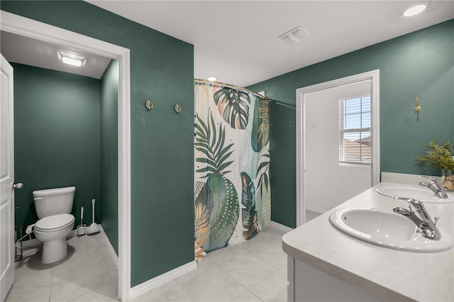 bathroom with double vanity, a sink, tile patterned floors, and toilet