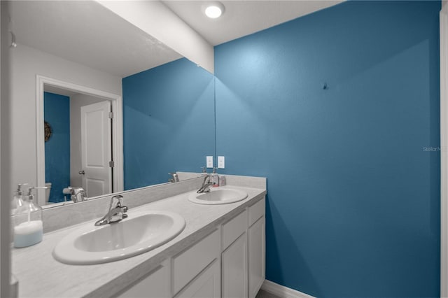bathroom with double vanity, a sink, and baseboards