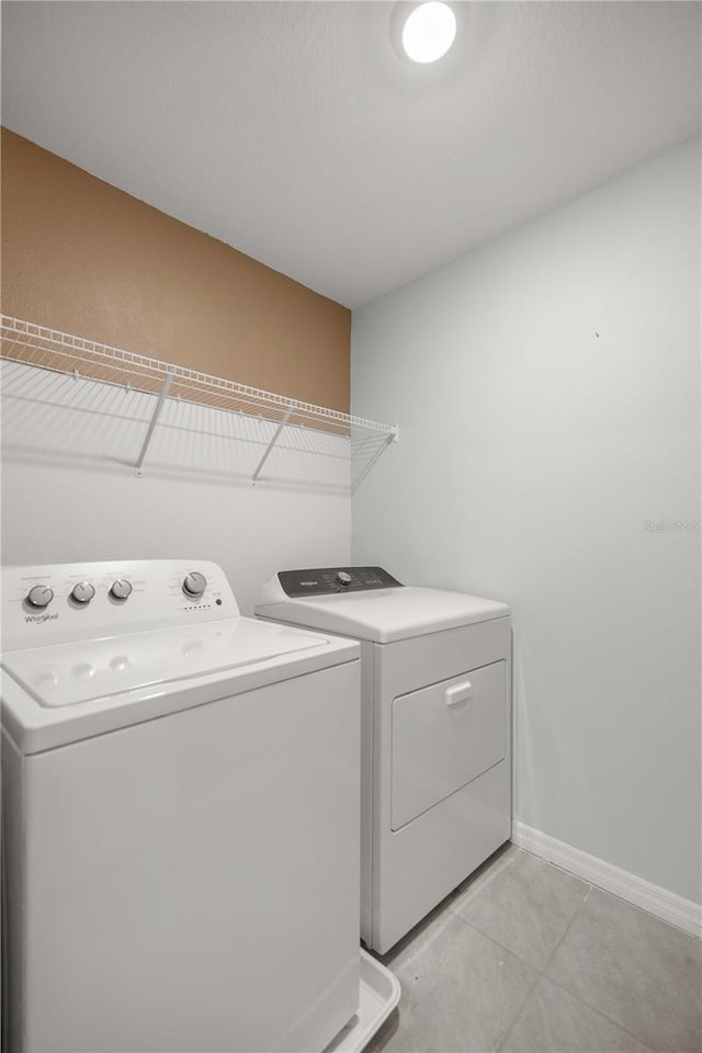 laundry room featuring laundry area, baseboards, light tile patterned floors, and washing machine and dryer
