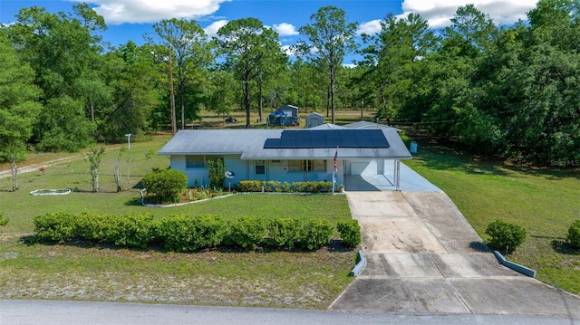 23737 NW Mallard Ave, Dunnellon, FL 34431 - view of front of house with concrete driveway, roof mounted solar panels, and a front yard