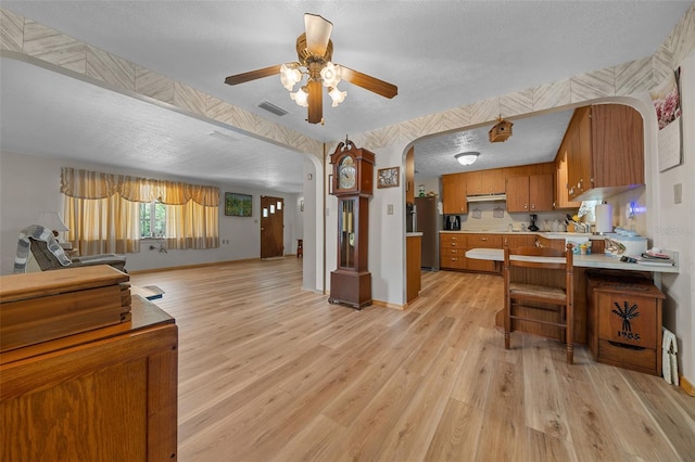 23737 NW Mallard Ave, Dunnellon, FL 34431 - kitchen with a textured ceiling, ceiling fan, arched walkways, brown cabinets, and light countertops