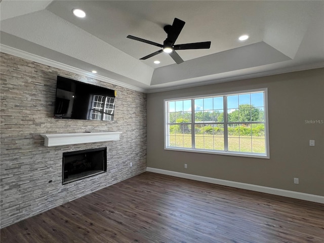 13430 NE 30th Ct, Anthony, FL 32617 - unfurnished living room featuring a tray ceiling, a stone fireplace, wood finished floors, a ceiling fan, and baseboards