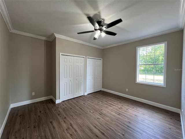 13430 NE 30th Ct, Anthony, FL 32617 - unfurnished bedroom featuring baseboards, dark wood-style floors, multiple closets, ornamental molding, and a ceiling fan