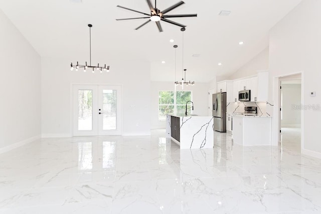 unfurnished living room with french doors, ceiling fan with notable chandelier, high vaulted ceiling, a sink, and marble finish floor