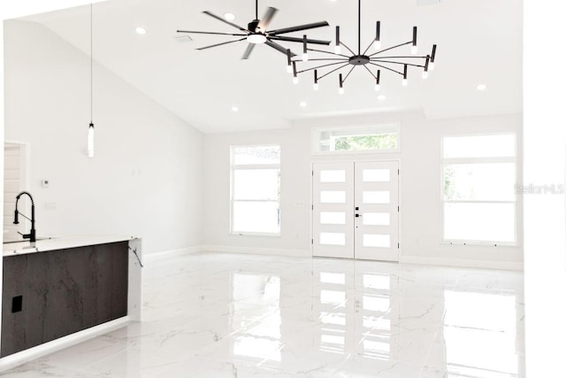 unfurnished living room featuring an inviting chandelier, high vaulted ceiling, baseboards, marble finish floor, and recessed lighting
