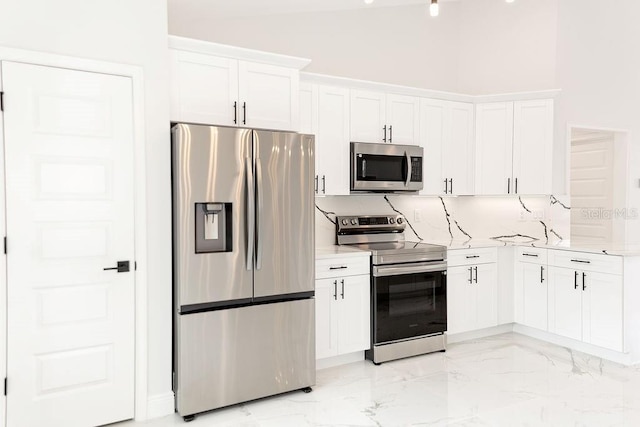 kitchen featuring stainless steel appliances, tasteful backsplash, marble finish floor, white cabinetry, and light stone countertops