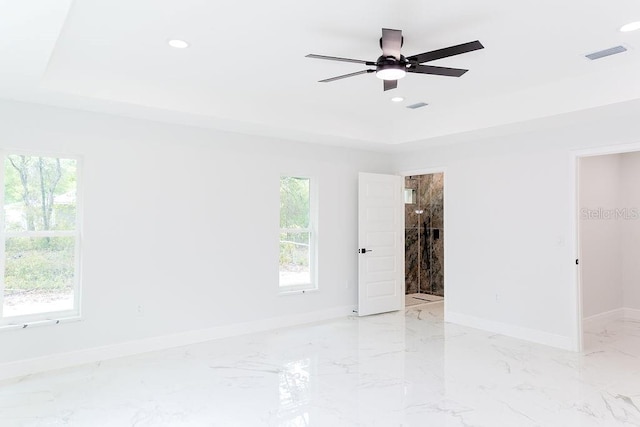 unfurnished room featuring marble finish floor, a tray ceiling, and recessed lighting