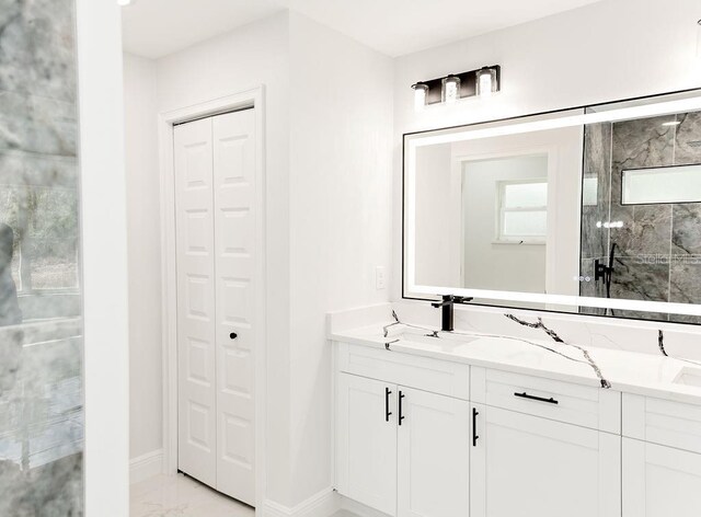 full bathroom with a stall shower, a sink, a closet, baseboards, and marble finish floor